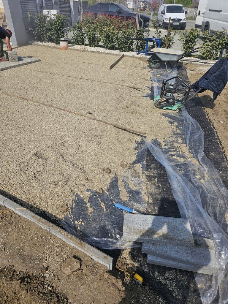 Nivelarea stratului de nisip calibrat pentru așezarea pavajului premium în curte din Giroc