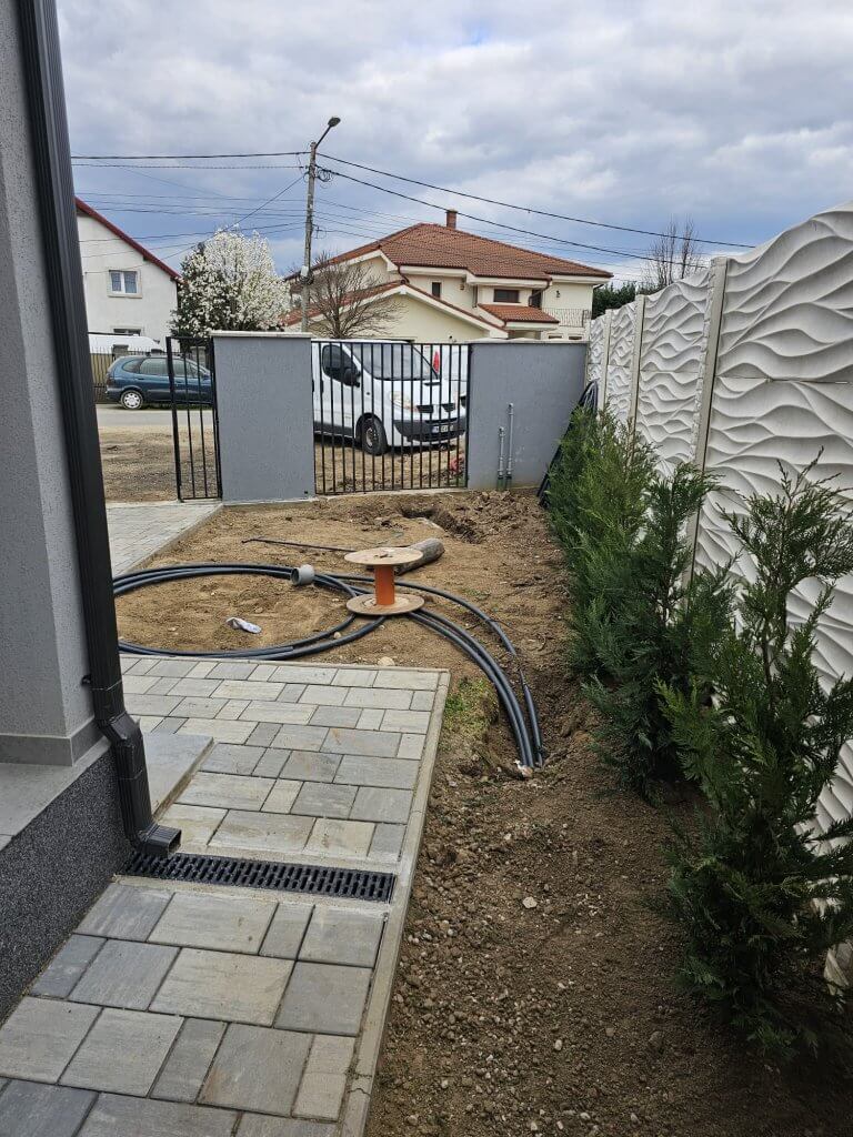 Pozare conducte sistem irigații automatizat în grădină din Giroc, cu leylandii plantați pe marginea pavajului